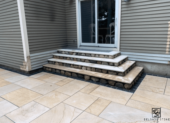 Photo of Cedar Creek River Rounds Natural Stone installed along outdoor steps and entryway landscaping.