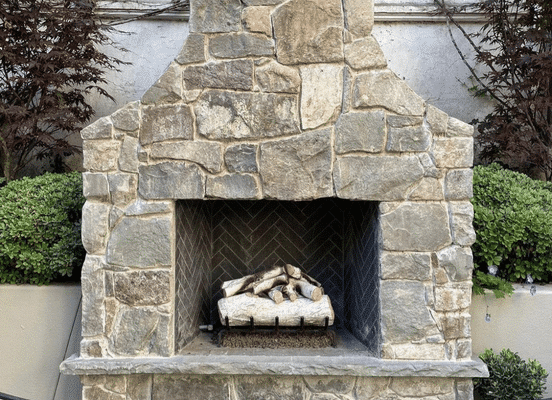 Photo of Fieldstone Dark Mosaic Natural Thin Stone Veneer installed on an outdoor fireplace surround.