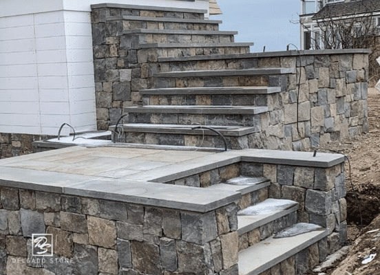 Photo of Fieldstone Dark Square and Rectangle Natural Thin Stone Veneer installed on outdoor stairs and retaining walls.