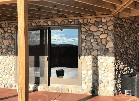 Photo of Newport River Rounds Natural Thin Stone Veneer installed on a covered patio and exterior wall.