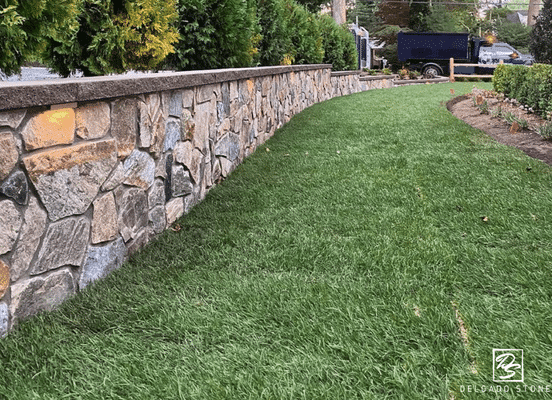 Photo of Nutmeg Ridge Mosaic Natural Thin Stone Veneer installed on a curved landscape retaining wall.