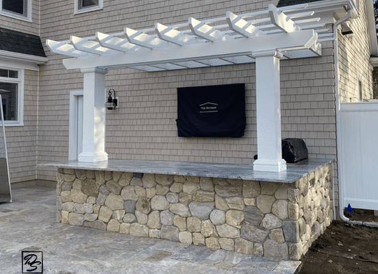 Outdoor kitchen coated in round stone veneer.