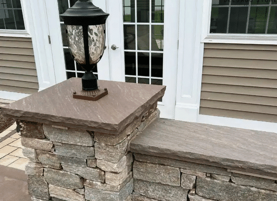 Photo of Colonial Tan Ashlar Natural Thin Stone Veneer installed on an exterior stone wall surrounding a residential property.