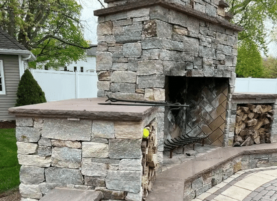 Photo of Colonial Tan Ashlar Natural Thin Stone Veneer installed on an outdoor grilling and pizza oven area in a backyard entertainment space.