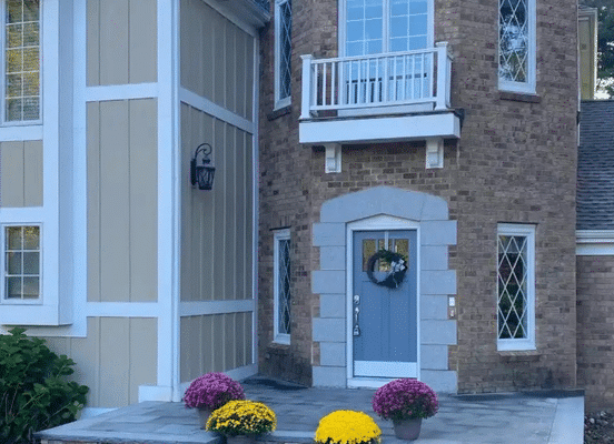 Photo of Colonial Tan Ashlar Natural Thin Stone Veneer installed as exterior wall cladding on a two-story house.